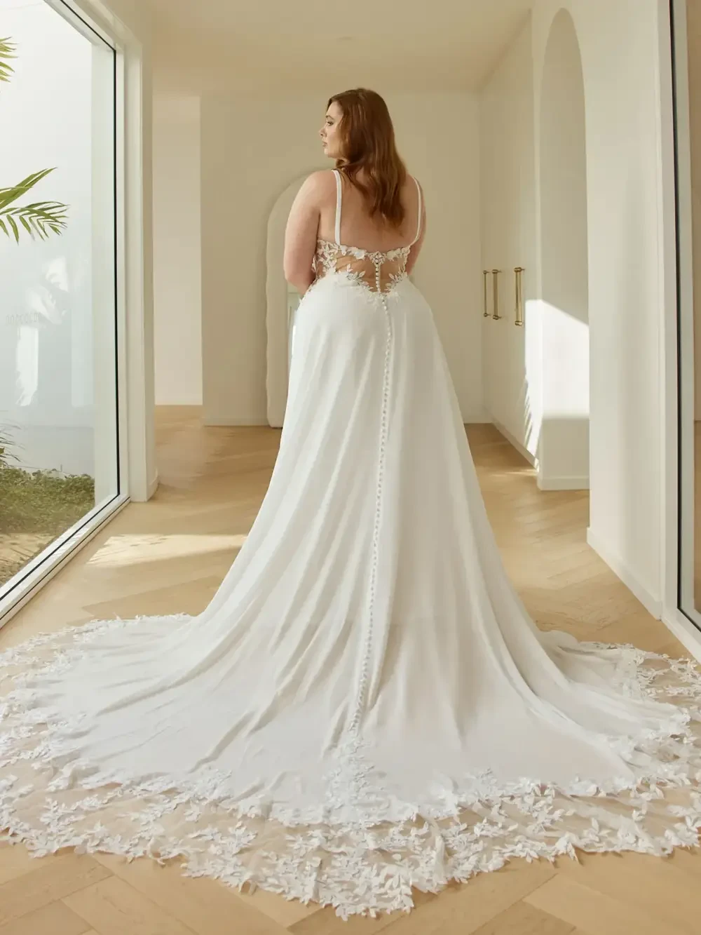 model is wearing a plus size sleeveless bridal gown