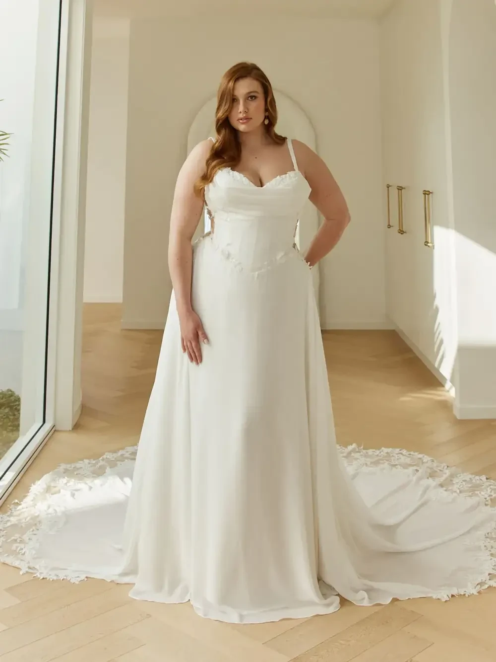 model is wearing a plus size sleeveless bridal gown